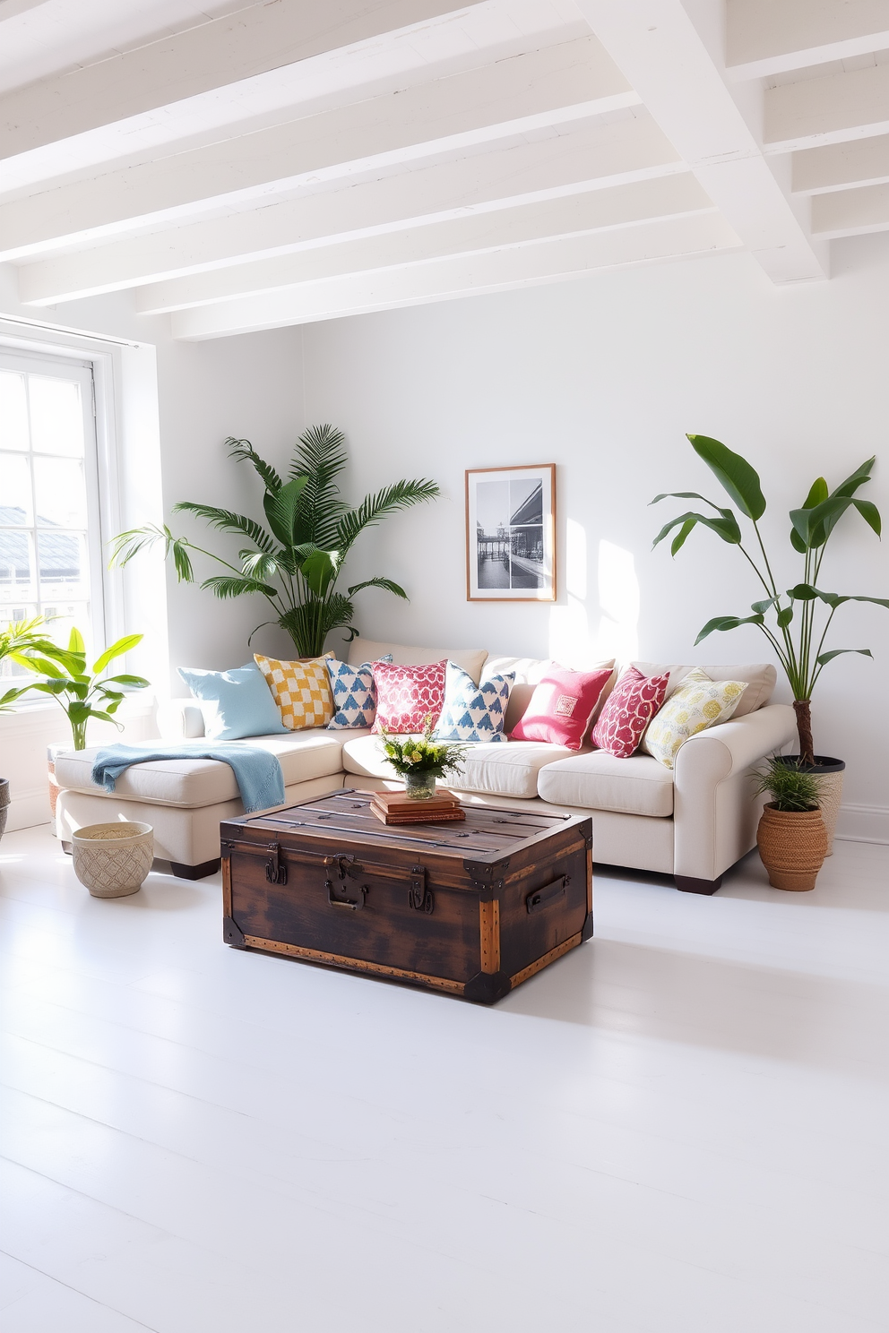 A bright and airy loft space filled with natural light. The focal point is a vintage trunk serving as a coffee table, surrounded by a cozy sectional sofa adorned with colorful throw pillows. The walls are painted in soft white, enhancing the summer vibe of the room. Potted plants are strategically placed around the space, adding a touch of greenery and freshness.